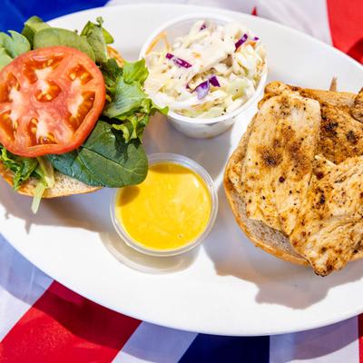 Chicken sandwich with lettuce, tomato, served with coleslaw and dressing
