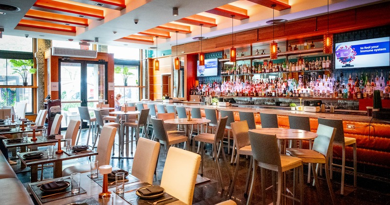 Interior, dining area, tables ready for guests, bar with stools, restaurant entrance