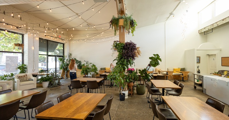 Spacious industrial-style cafe interior space, seating area with wooden tables and dark chairs