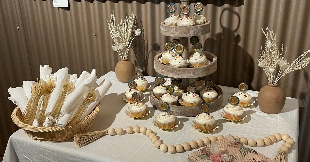 Dessert display table featuring a rustic three-tiered cupcake stand