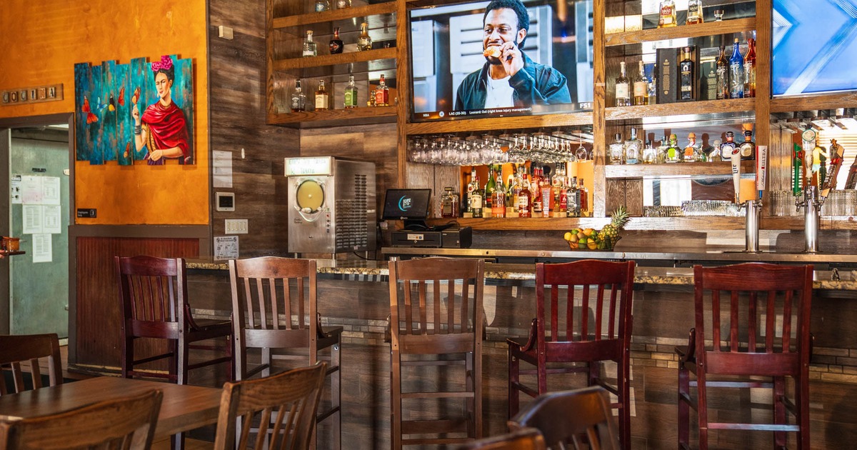Interior, bar area, marble top bar with wooden stools, drink shelves behind, TV on the wall