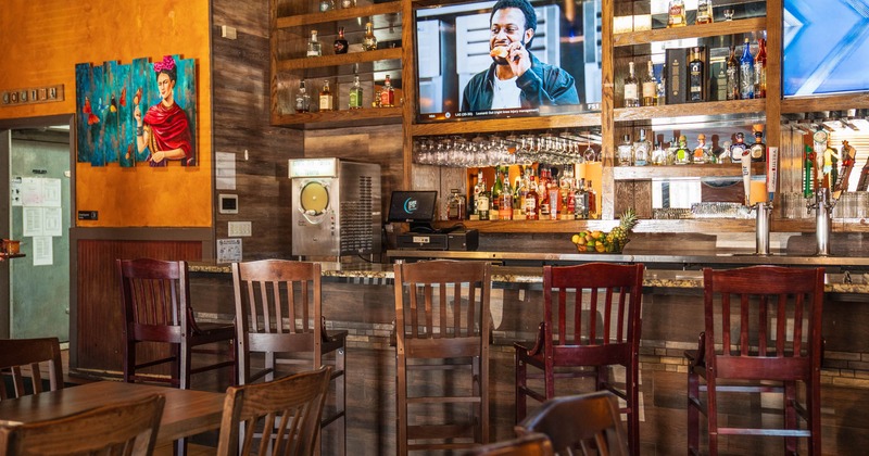 Interior, bar area, marble top bar with wooden stools, drink shelves behind, TV on the wall
