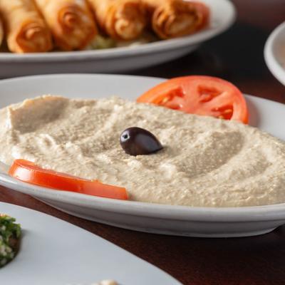Hummus with tomato slices and a black olive on top.