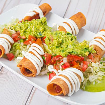 Taquitos, topped with pico de gallo, cream, and guacamole.