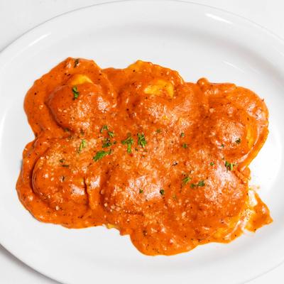 Lobster Ravioli in creamy, tomato-based sauce, garnished with chopped herbs.