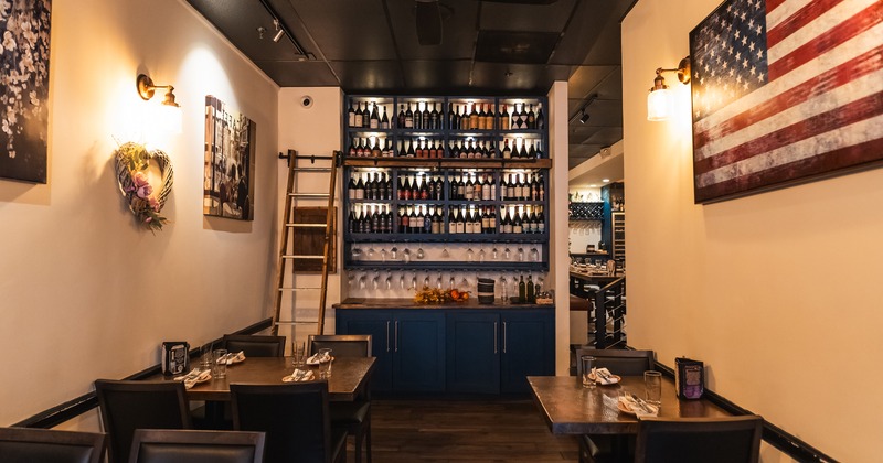 Cozy interior dining area with set tables and a tall wine shelf over the wall