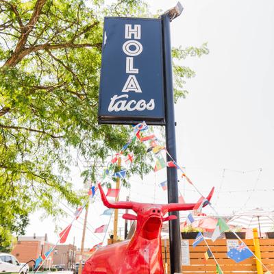 Restaurant outdoor signage featuring a distinctive red bull statue in front.