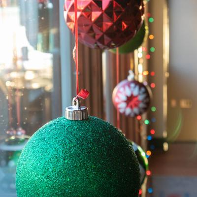 Close-up of glittery Christmas ornaments hanging by red ribbons.