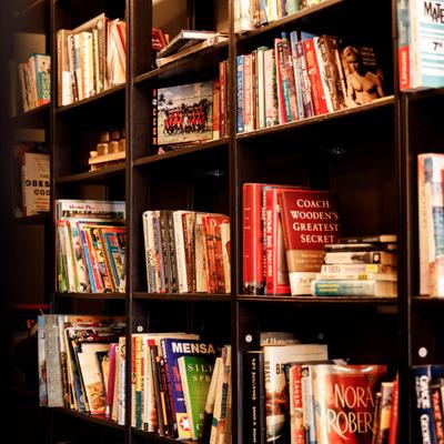 Numereus books arranged on a dark wooden shelves.