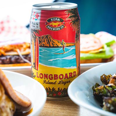 A vibrant can of beer surrounded by plates of food.