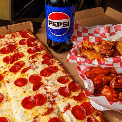 A large pepperoni pizza beside chicken wings and a bottle of soda.