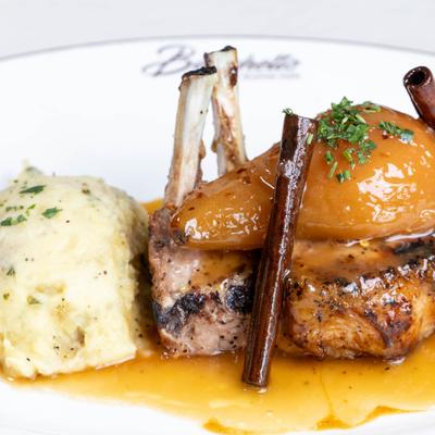 Pork chop topped with a ripe pear soaked in apricot preserves, served with mashed potatoes.