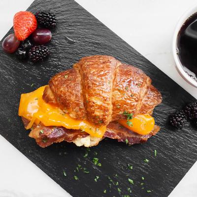 Croissant with scrambled eggs, bacon, and cheddar.
