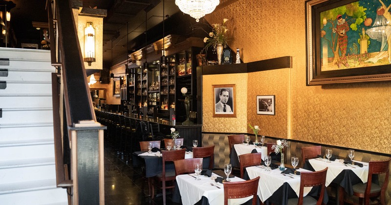 Dining tables, the bar is at the back, and the stairs to the upper floor are on the left