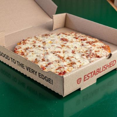 Gluten free pizza in an open box on a table.