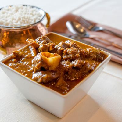 Nepalese style Goat meat cooked with herbs and spices, with a side of steamed rice.