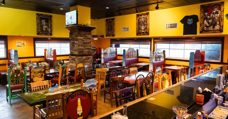 Interior of Mexican restaurant with colorful wooden tables and chairs.