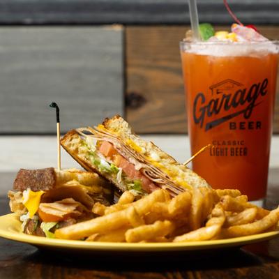 Club sandwich served with fries, beside a cocktail.