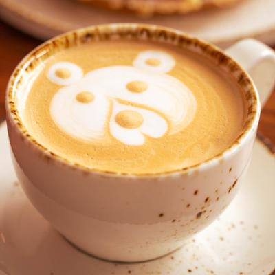 A cup of latte with latte art in the shape of a bear face.