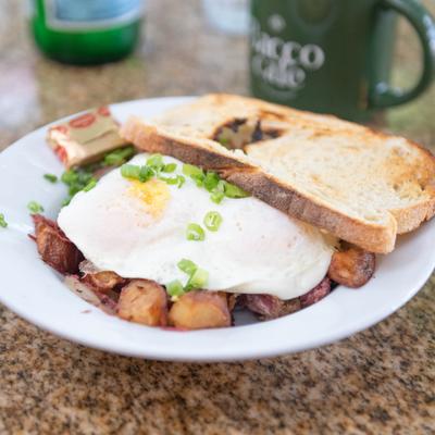 Corned beef hash topped with fries eggs, scallions. and toasted bread slice.