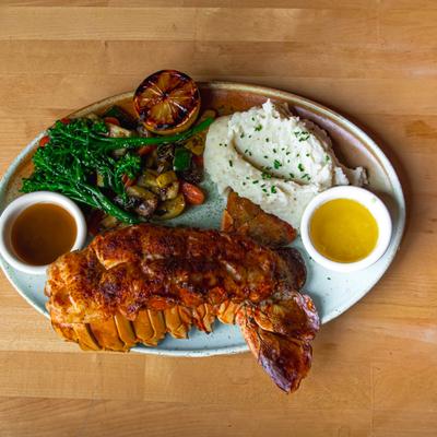 Lobster tail with mashed potatoes, broccolini, and two dipping sauces.