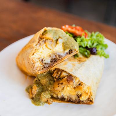 Chorizo burrito sliced in half and served with a side salad.