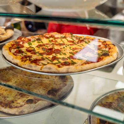 Pizza with pepperoni, cheese, and pesto.