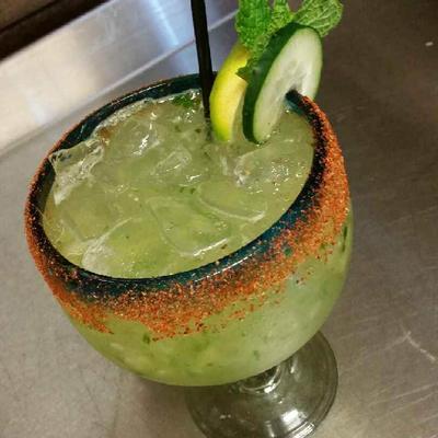 Cocktail served in rimed glass, garnished with cucamber, lemon and mint spring.