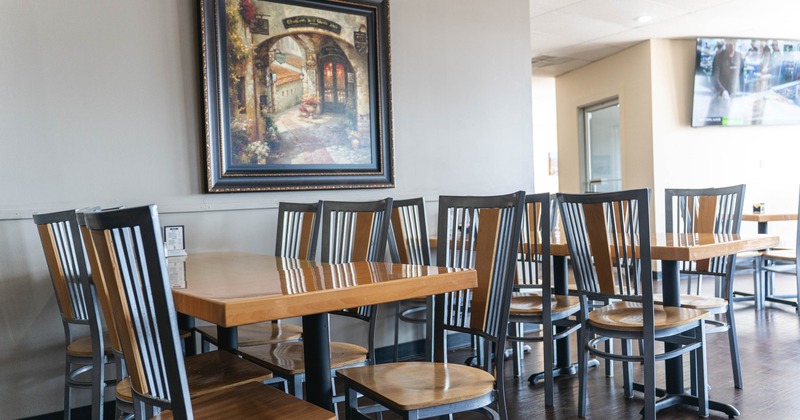 Interior - wooden tables and chairs, framed painting on the wall and TVs in the background