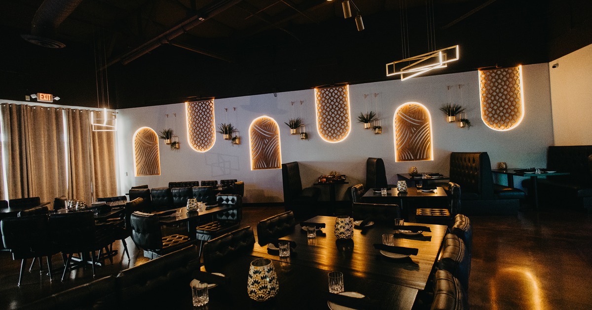 Modern interior dining area with dark upholstered chairs, booths, and set tables