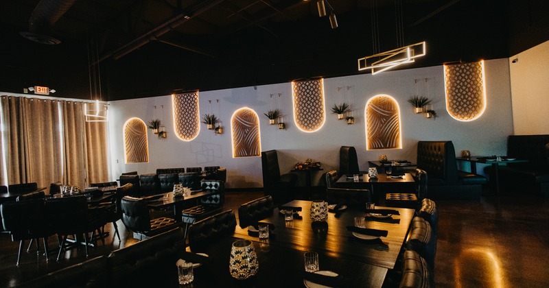 Modern interior dining area with dark upholstered chairs, booths, and set tables