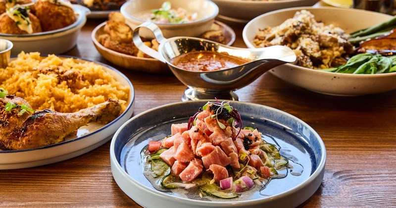 A variety of dishes are arranged on a wooden table