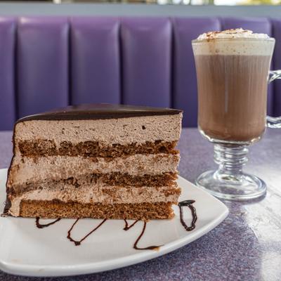 Piece of cake with hot chocolate served on the table.
