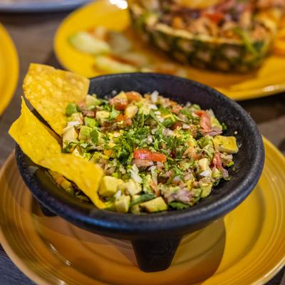 Mexican guacamole served in a stone mortar with tortilla chips.