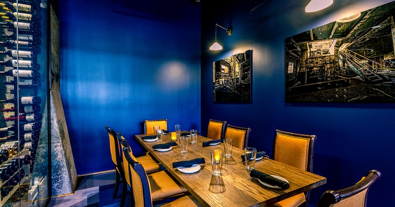 Interior, set dining table in a corner with dark blue walls decorated with pictures