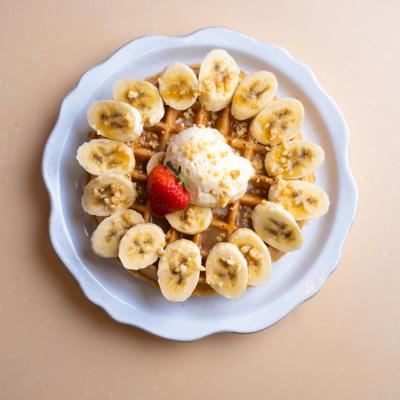 Belgian waffle topped with sliced bananas, macadamia nuts and ice cream.