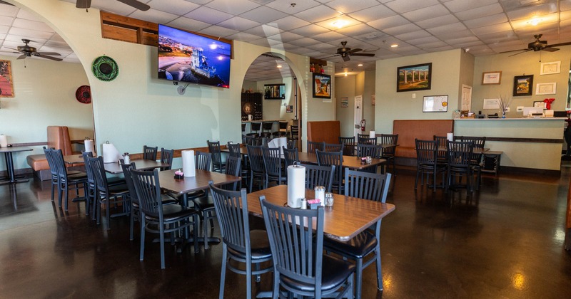 Spacious dining room with dark floors, wooden tables, and booth seating