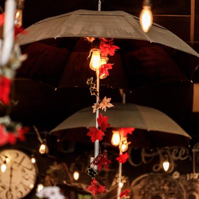 Umbrellas hanging from ceiling with lights and leaf decorations.