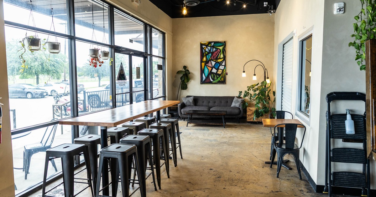 Interior, high seating wooden top table with stools, entrance, large shop window, cozy sofa