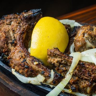 Grilled lamb chops with onions and a lemon wedge, close-up.