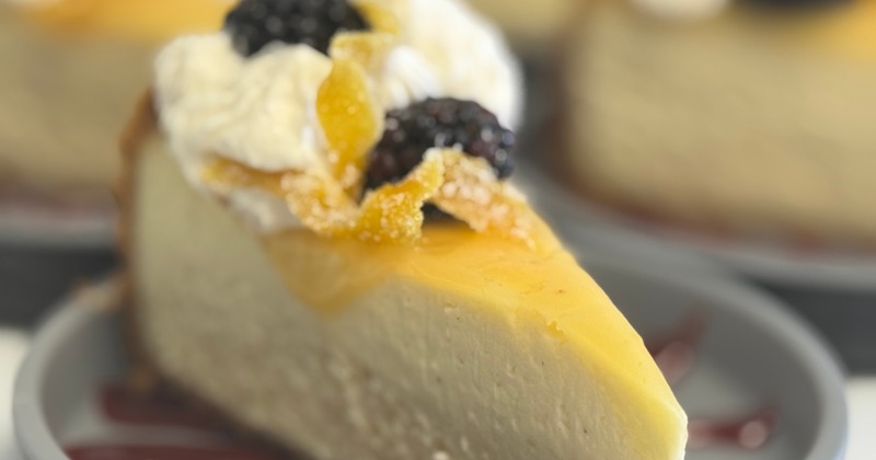 Slice of cheesecake topped with whipped cream and fresh blackberries