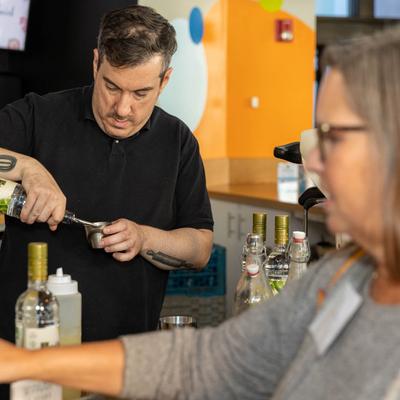 Bar staff pouring a drink.