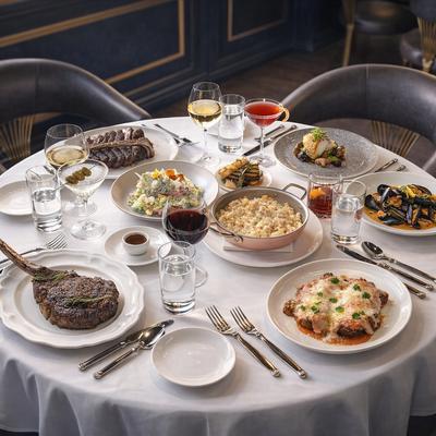 Table filled with assorted plated dishes, condiments and drinks.