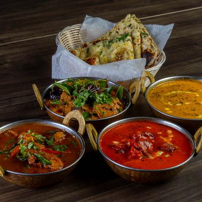 Assorted curries with basket of naan flatbread.