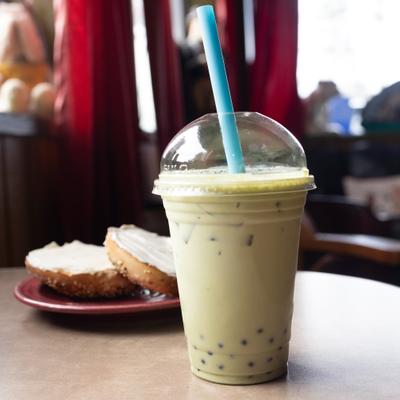 Matcha Boba Tea served on a table with a cream cheese bagel.