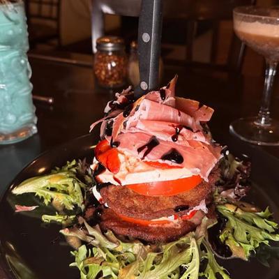 Layered eggplant parmesan salad with mozzarella, sliced prosciutto, and balsamic glaze.