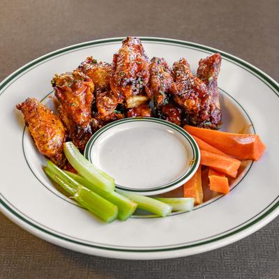 Chicken wings on a plate with ranch dressing and carrots and celery.