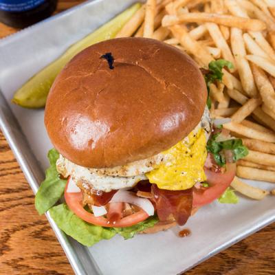 Double Take Burger topped with fried egg,  BBQ sauce, lettuce, tomato and onion, served with fries.