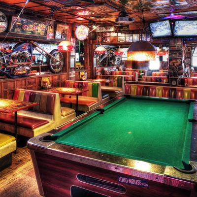 Colorful bar interior with vibrant booth seating, a green pool table, and retro decor