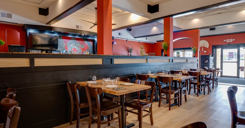 Interior with wooden tables, red walls, and a dragon mural behind the bar.